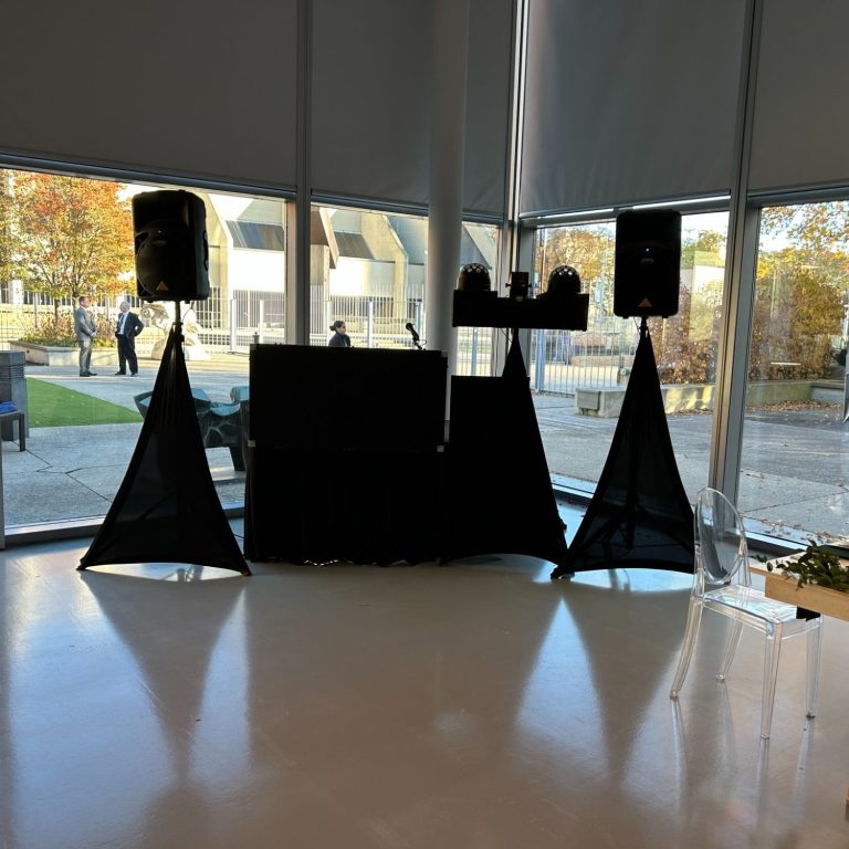 A DJ setup with speakers and a table in a bright, modern venue.