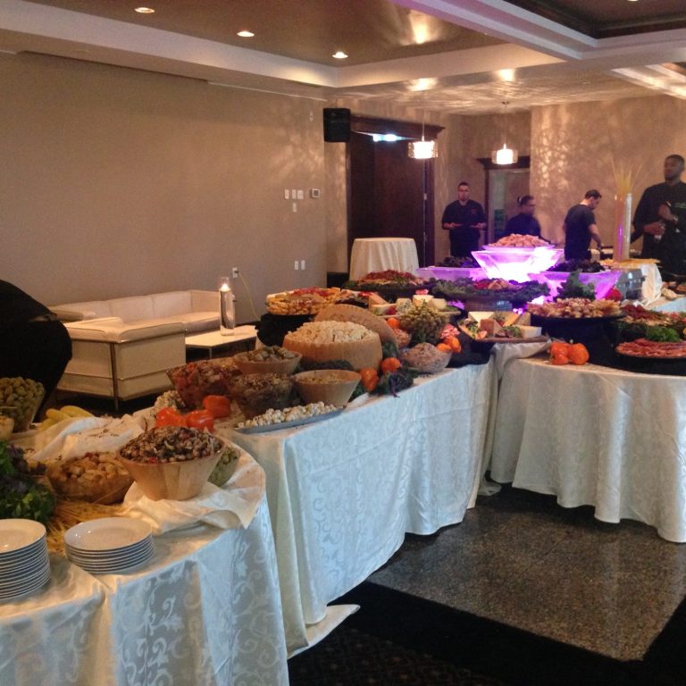 A lavish buffet with various dishes and decorations on elegantly draped tables.