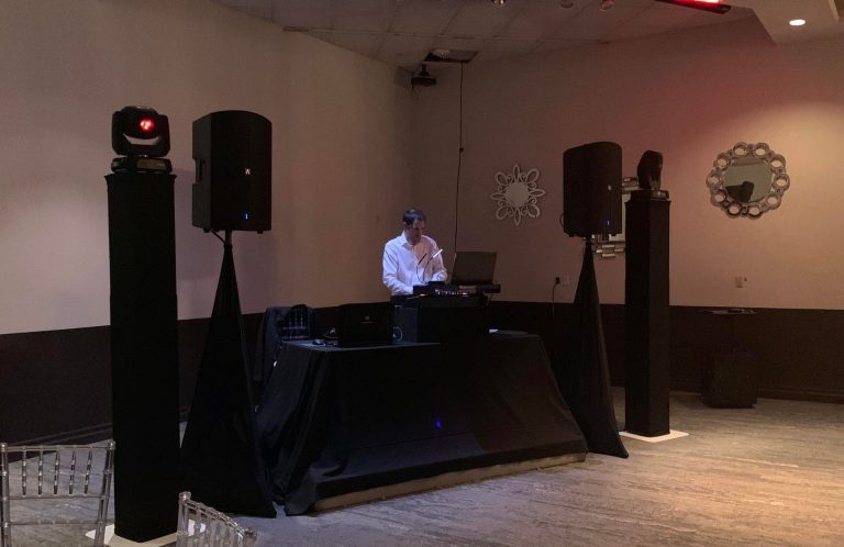 Vip DJ Package DJ performing in a venue with speakers and Intelligent Lighting