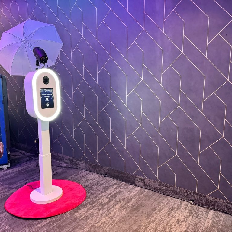 Photo booth with an umbrella, set against a geometric patterned wall.