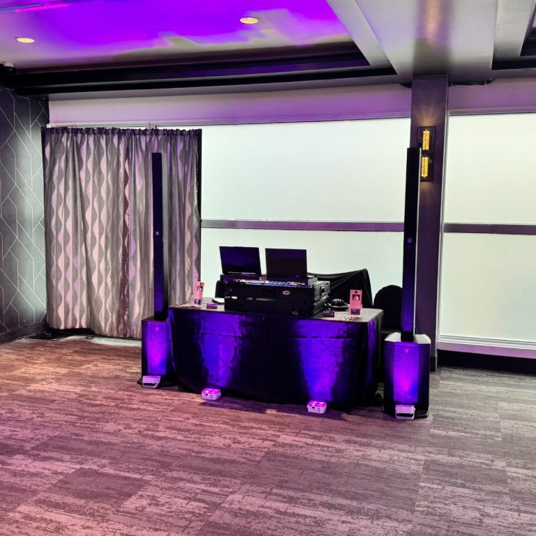 DJ setup with two turntables and speakers in a dimly lit room.