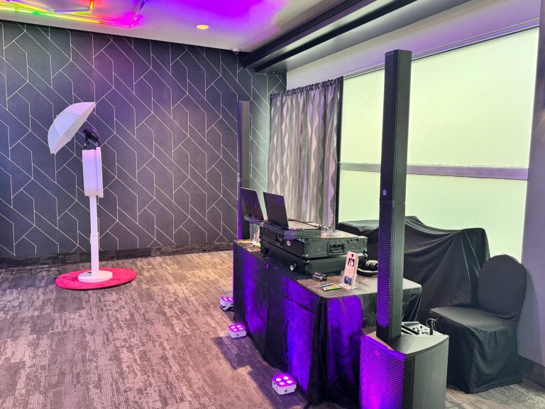 A modern event setup featuring audio equipment and a photo booth with purple lighting.