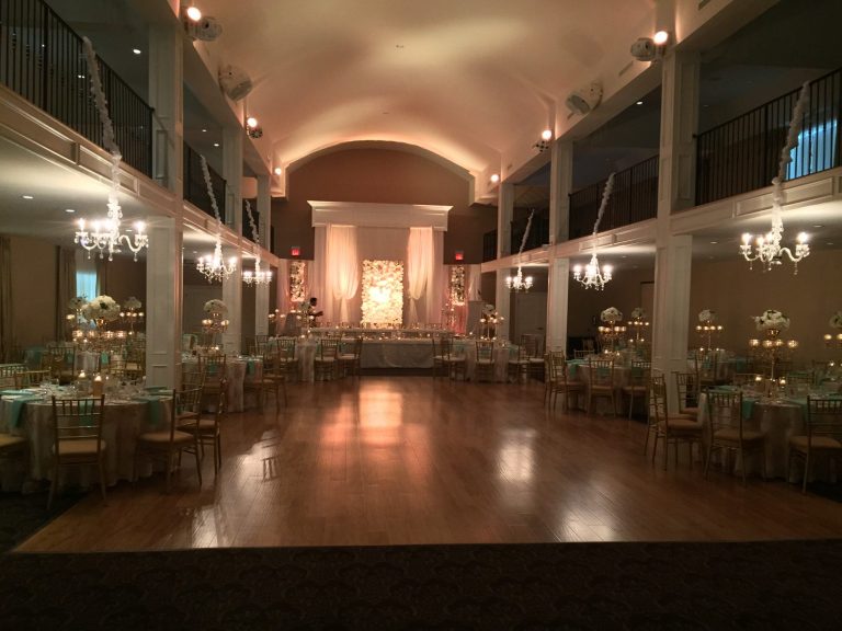 Elegant banquet hall with chandeliers, wooden floor, and arranged dining tables.