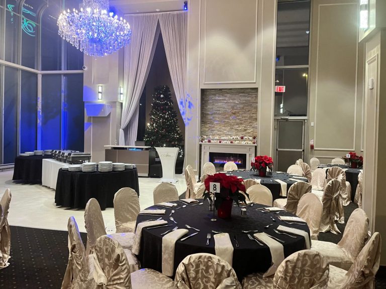 Elegant event space with black and white decor, round tables, and a chandelier.